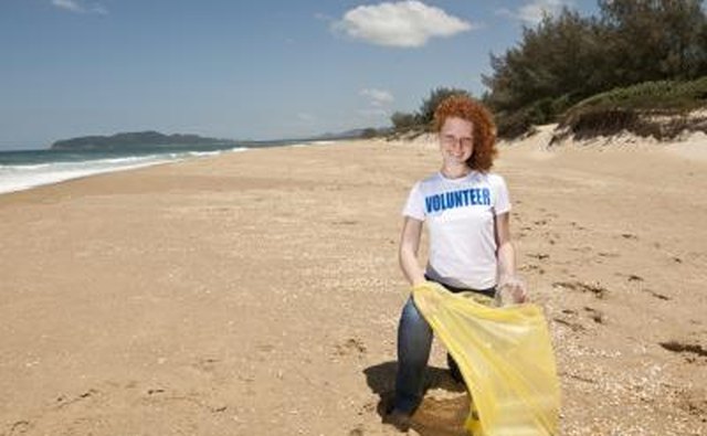 Young volunteer with garbage bag cleaning beach