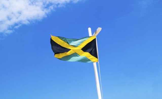 A Jamaican flag flying on the mast of a boat.