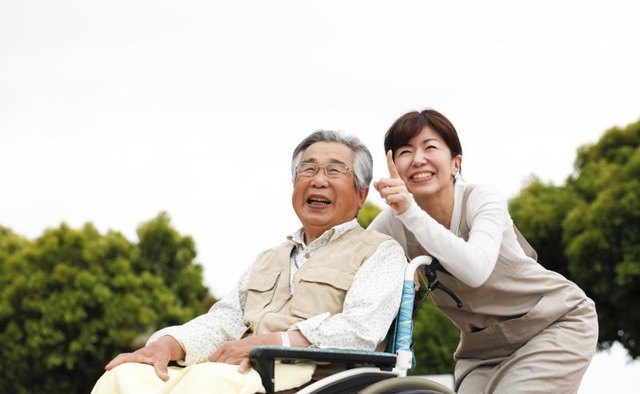 Senior man in wheelchair accompanied by his daughter