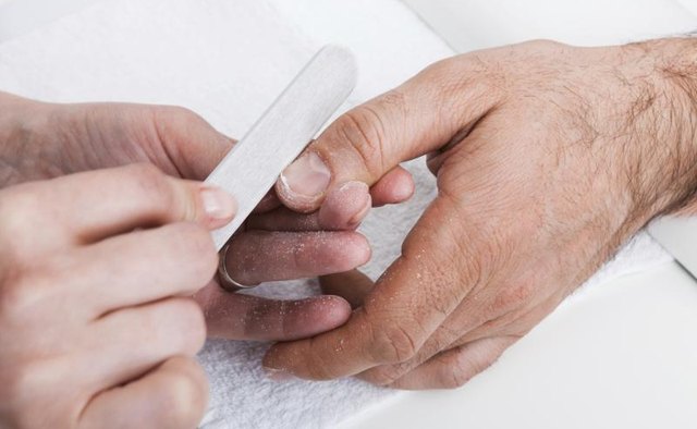 Man's hands getting a manicure.