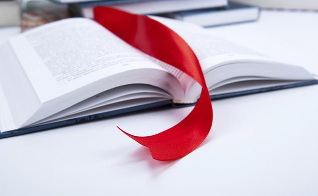 A red ribbon book mark in an open book.