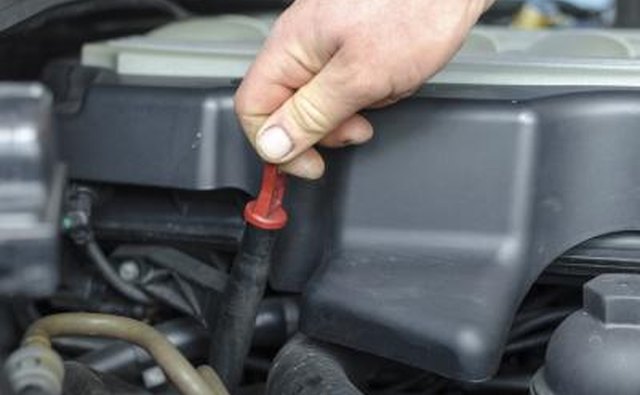 man checking oil level in car engine