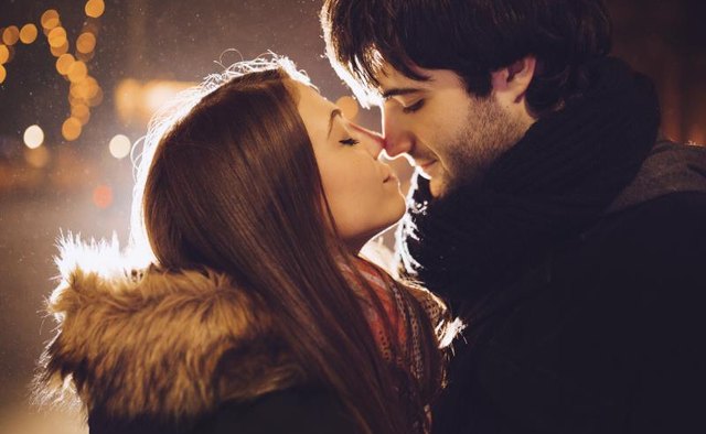 A young couple about to kiss at night.