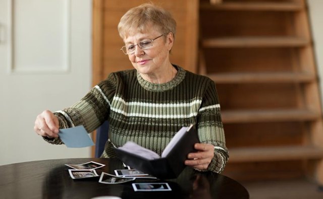 Mature woman putting photographs into an album.