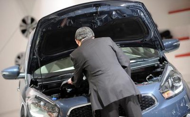 Man inspects engine of a KIA automobile