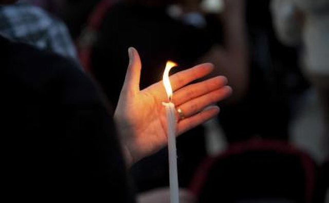 A woman holds a candle at a religious vigil.