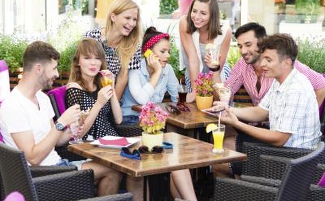 Social group of young adults meeting in sidewalk cafe.