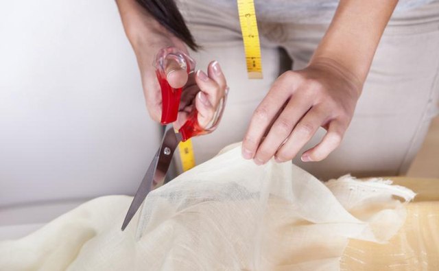 Close-up of a woman cutting a piece of fabric.