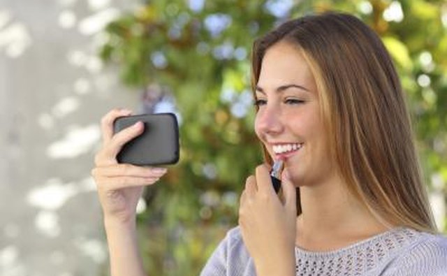 Teenage girl putting on lipstick