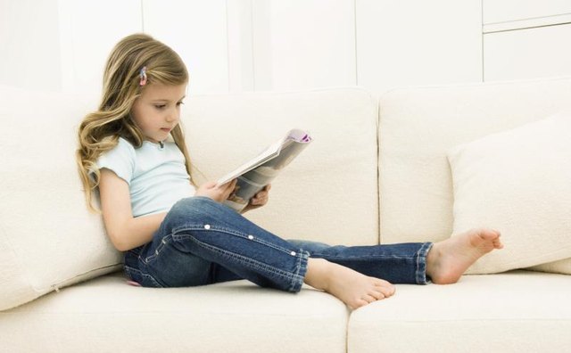 Young girl reading a magazine on the couch.