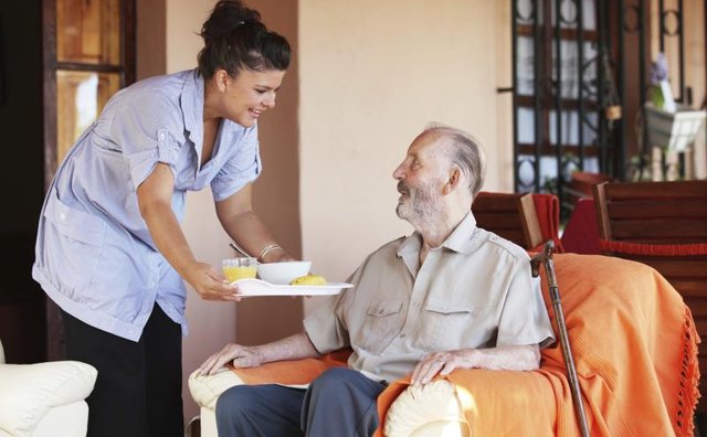 A woman serving a senior a meal.