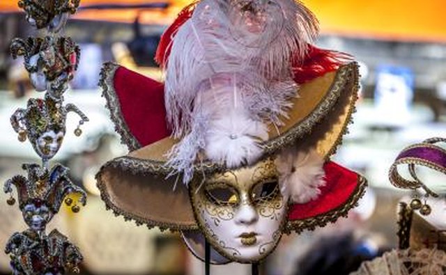 A Mardi Gras mask and feathered hat on a mannequin in a costume shop.