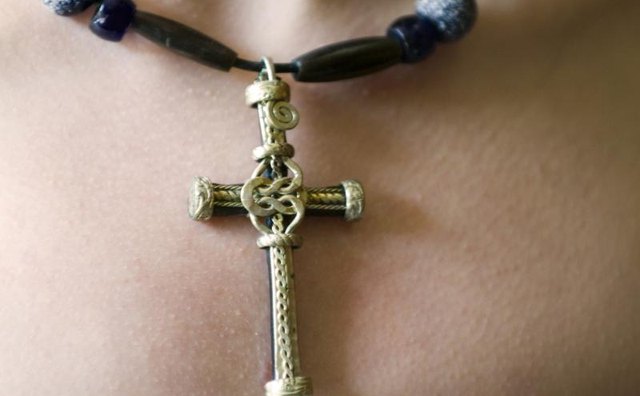 Close-up of a Christian cross worn as a pendant around a woman's neck.