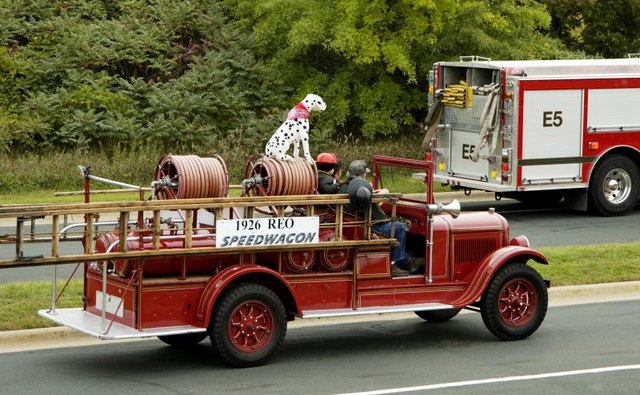A Dalmatian sits on top of a fire engine.