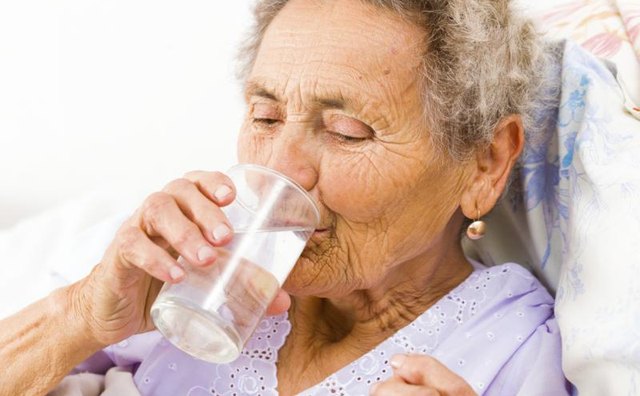 Senior woman swallowing pill with glass of water