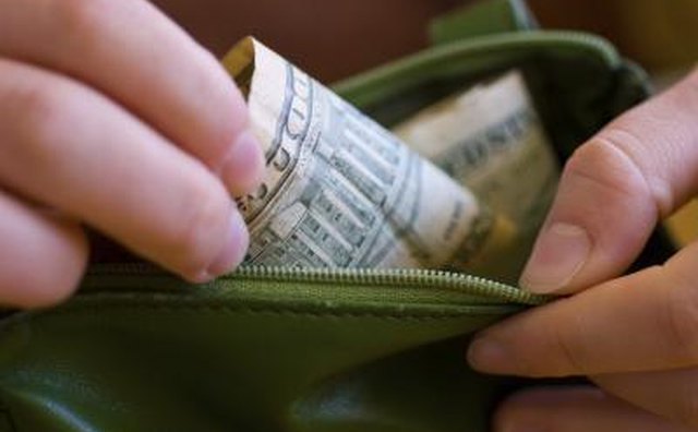 A close-up of a woman taking money out of her wallet.