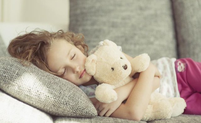 Girl sleeping with a stuffed teddy bear.