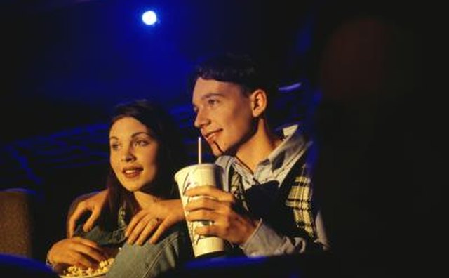 A young couple sharing a drink in a movie theater.