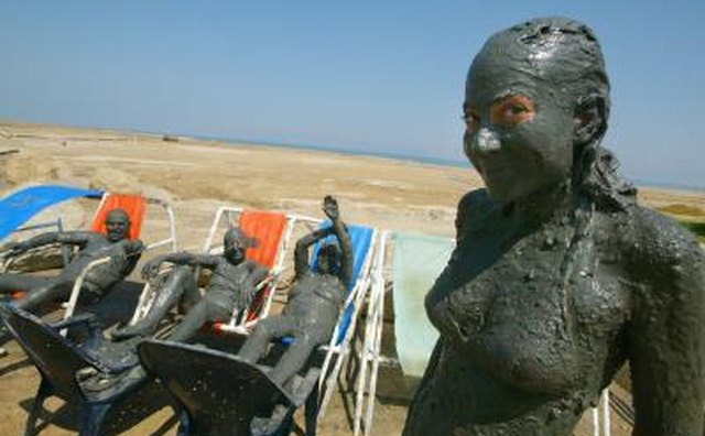 Tourists covered in mineral mud at spa resort on the Dead Sea shoreline