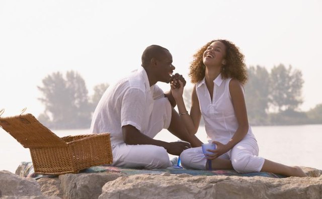 A couple having a romantic picnic in front of a lake.