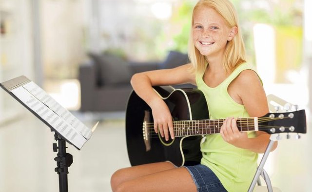 Girl holding guitar next to sheet music