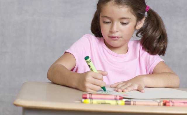 Young girl coloring at table.
