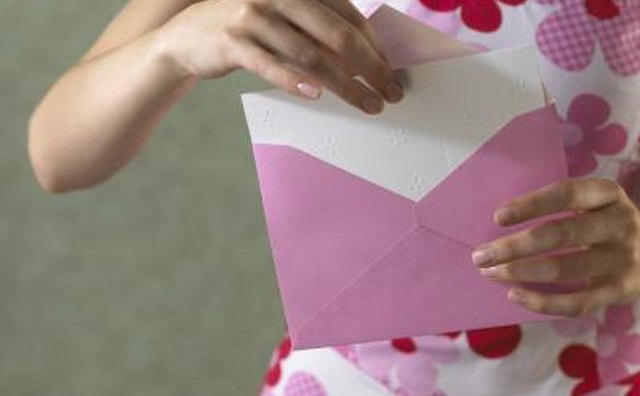 Woman taking card out of handwritten envelope.