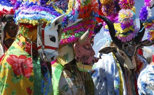 People in a parade wear Mexican masks and costumes.