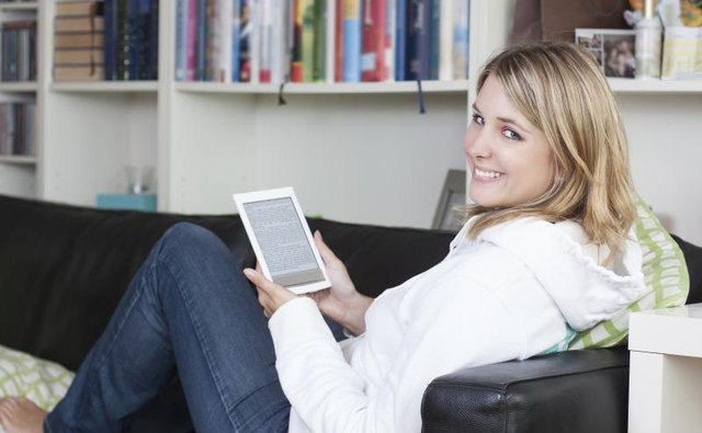 Woman reading an ebook on a sofa.
