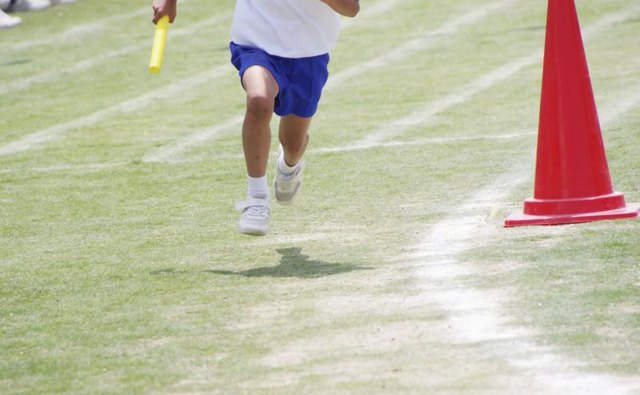 A teenaged boy running in a relay race.