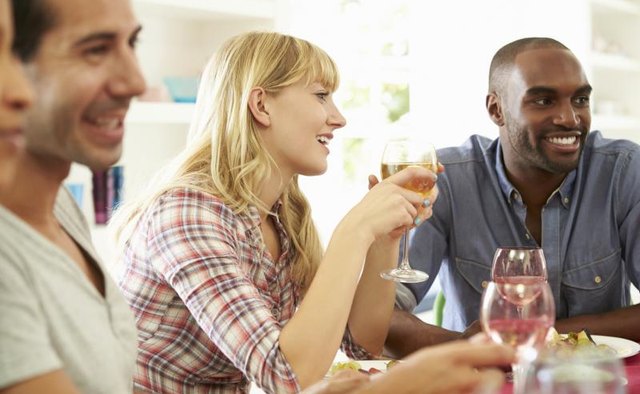 People laughing over pleasant conversation at a dinner party.