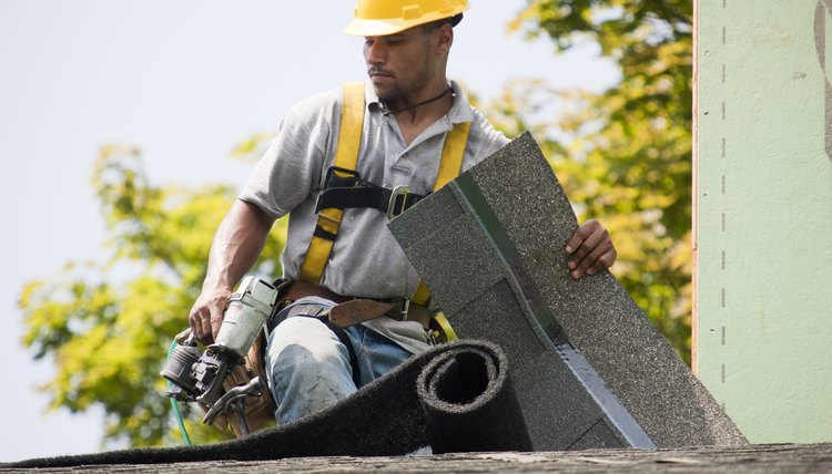 Roofer working on shingling a new roof