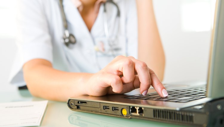 Woman doctor pushing key on laptop computer