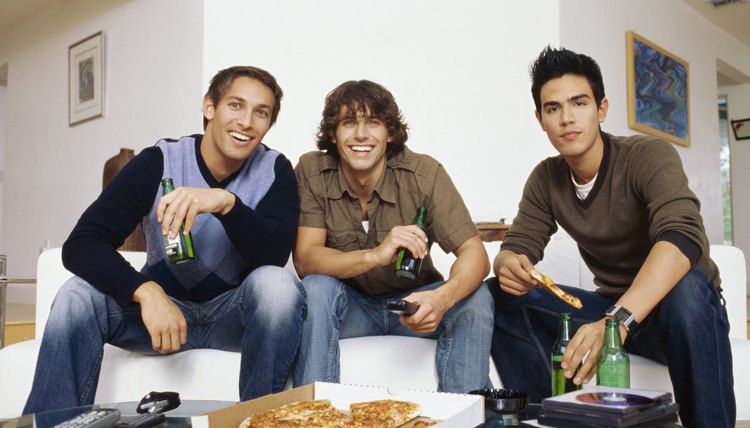 Three young men sitting on the sofa, drinking beer