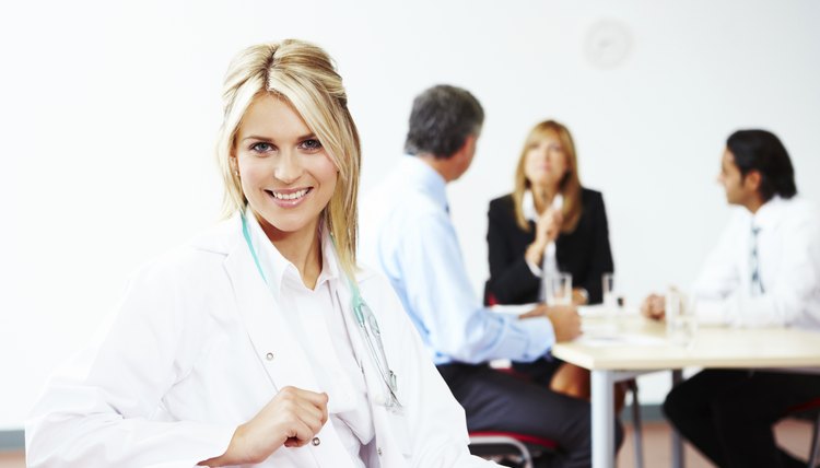 Portrait of happy Female Doctor with colleagues behind