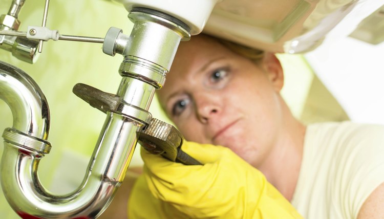 Housewife repairing a siphon under the sink