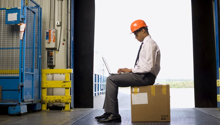 Businessman working on laptop in warehouse