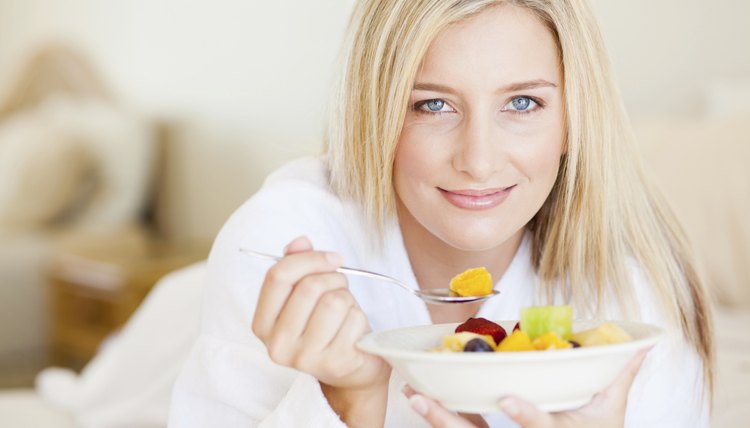 young woman eating breakfast in bed