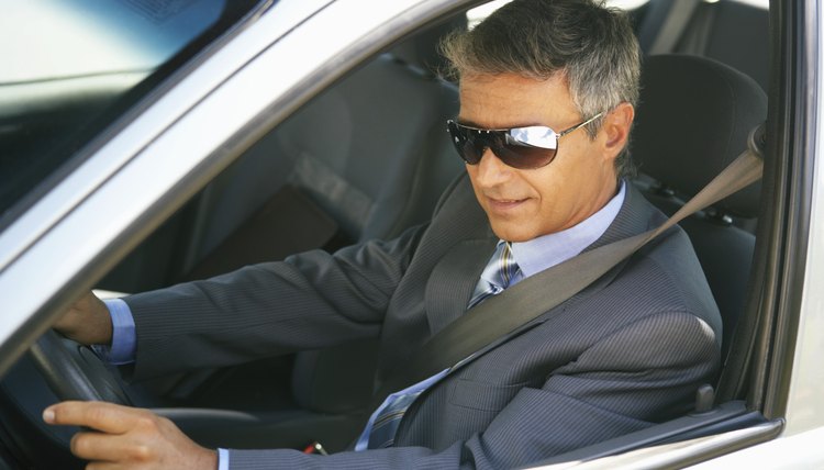 Businessman wearing shades in car, close up, elevated view