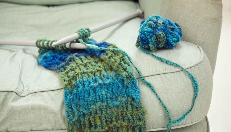 Knitting needles and scarf on chair