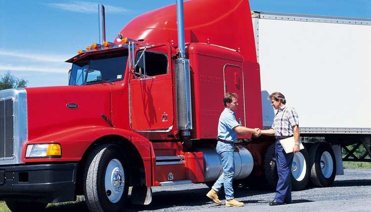 Men shaking hands beside semi