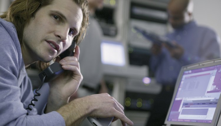 Computer technician holding two telephones