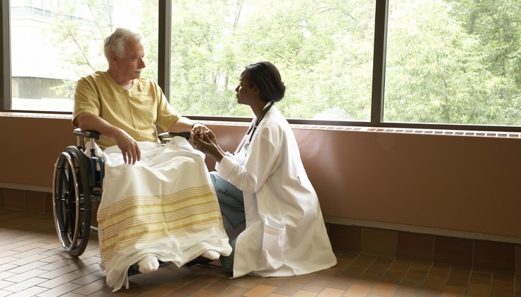 Doctor comforting patient in wheelchair by windows in hospital