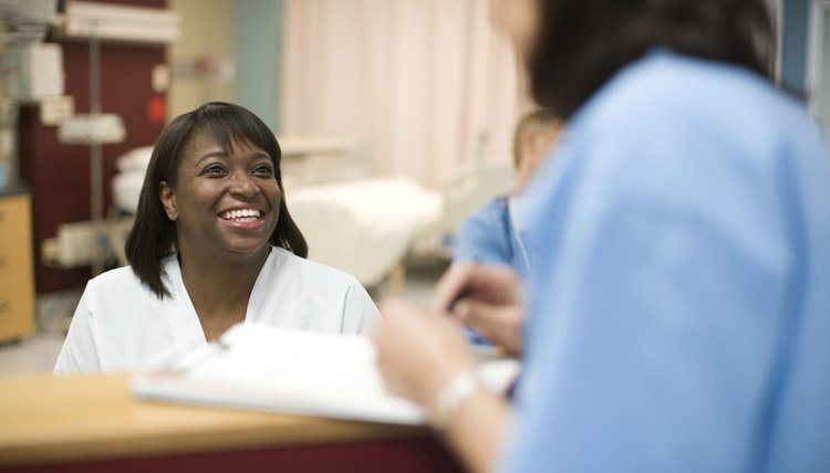 Female nurse talking to doctor at desk in hospital