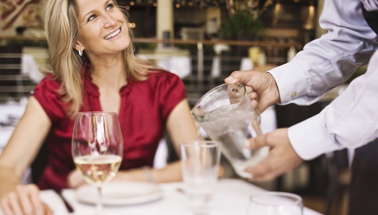Server pouring water for woman