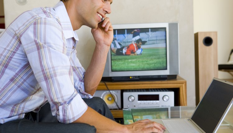 Man using cellular phone while on laptop