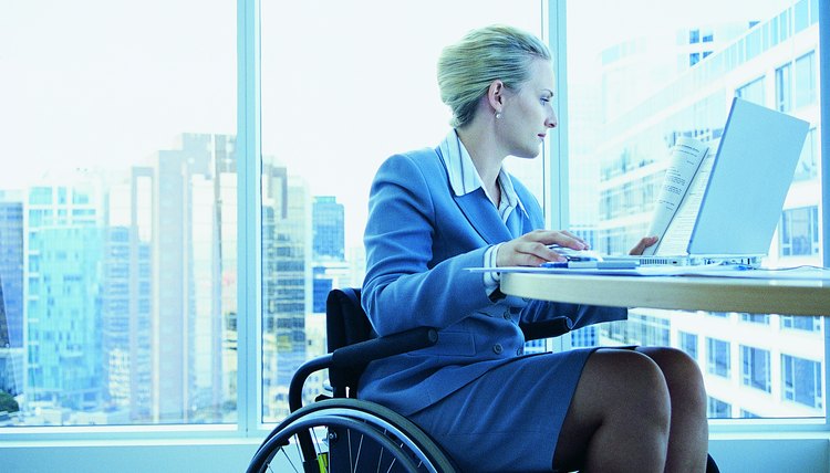 Businesswoman Sitting in a Wheelchair Working on a Laptop in the Office
