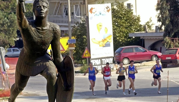 Runners in Greece pass a statue of the Pheidippides in 2002.