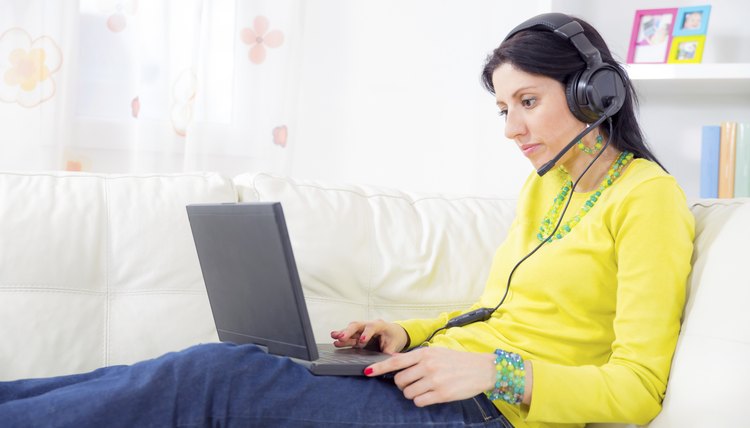 woman on sofa using laptop and headset at home