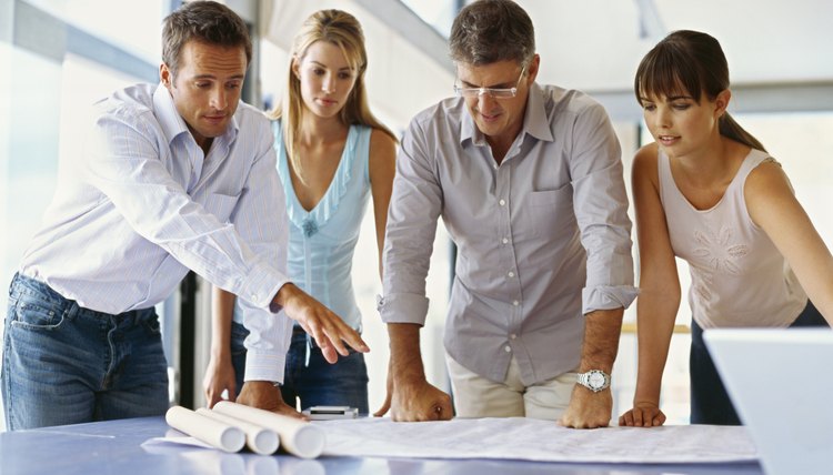 group of business executives looking at a blueprint in an office